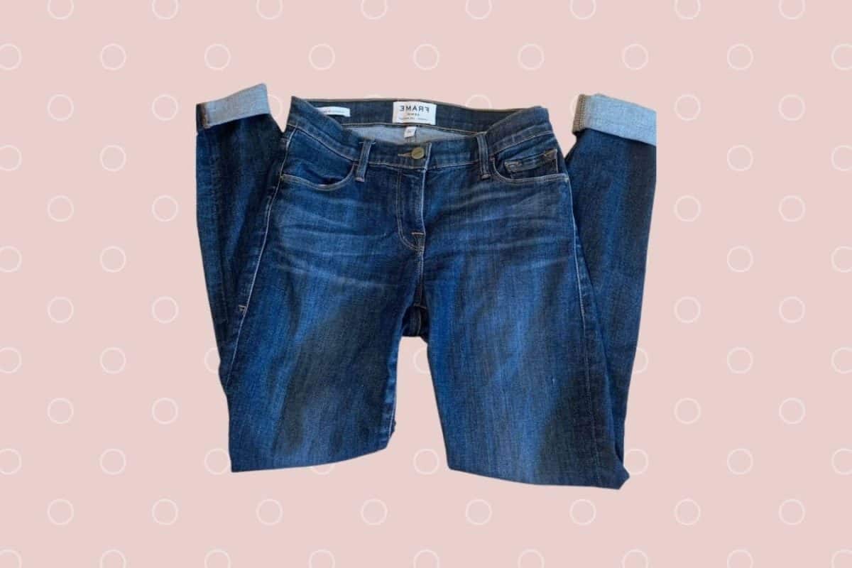 Mid-rise folded denim jeans placed on a pink background