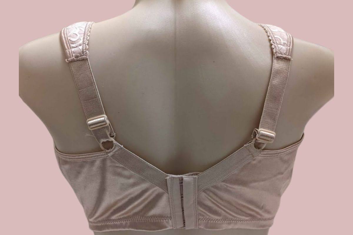 A back view of a cream full-coverage bra with thick straps placed on a mannequin