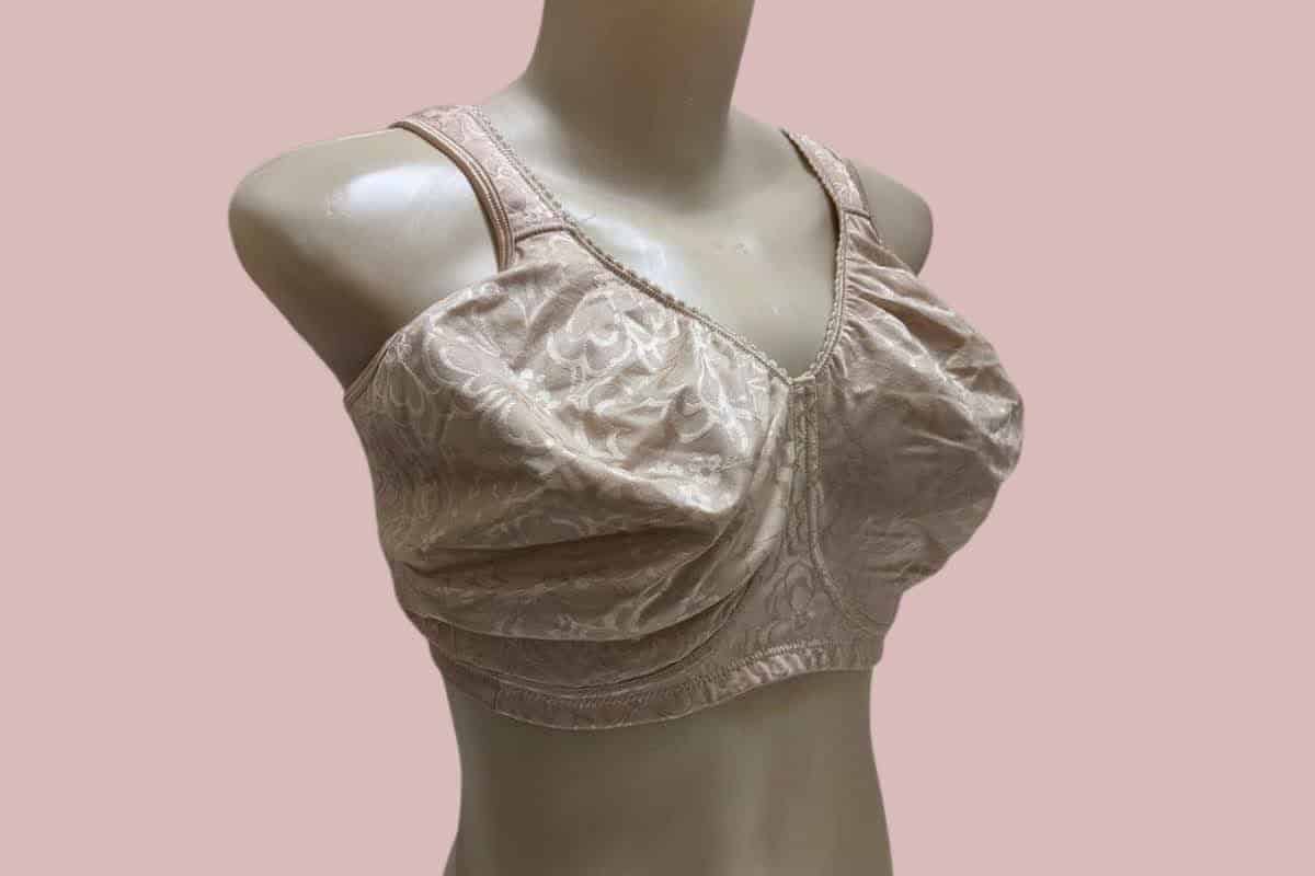 A cream full-coverage bra with thick straps and a wide bra band placed on a white mannequin