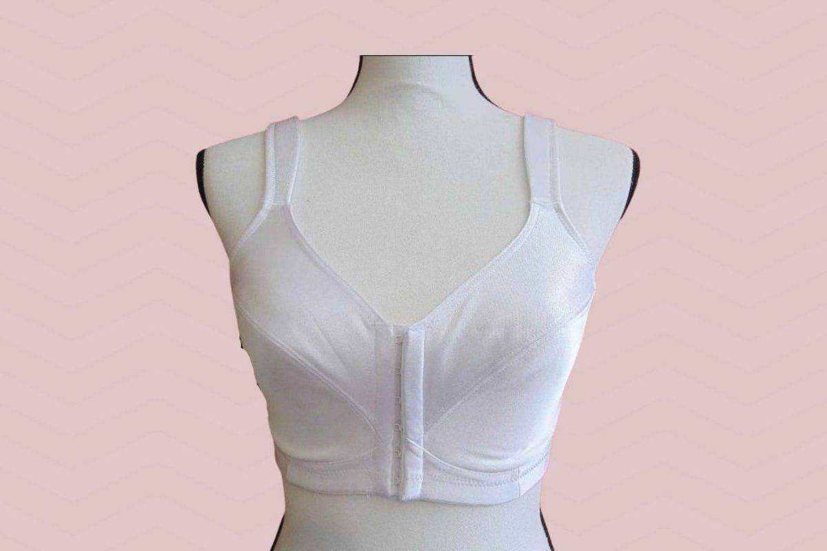 A white front clasp bra is placed on a white mannequin on a pink background