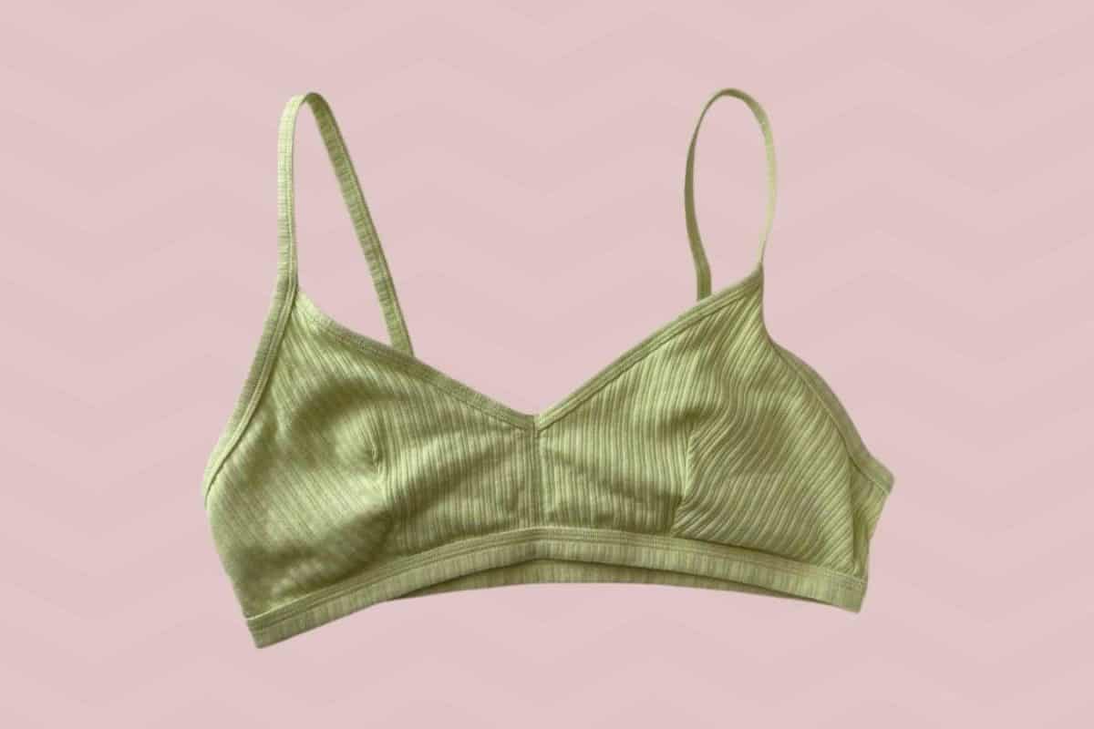 A green spaghetti strap pullover bra placed on a pink background