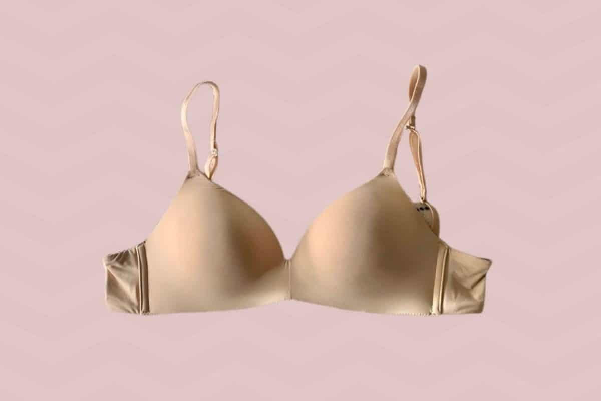 Wire-free regular bra nude in color with adjustable straps placed on a pink background