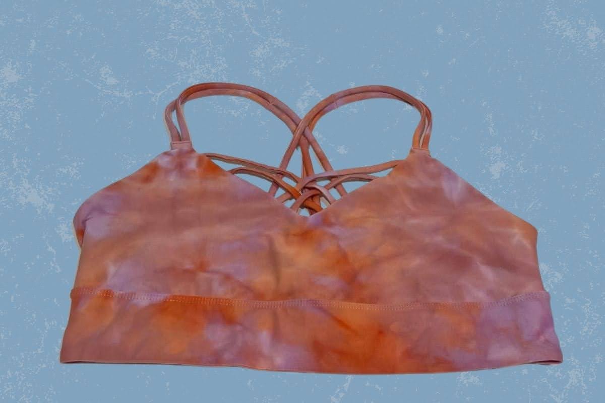 A wireless tie dye sports bra placed on a blue background