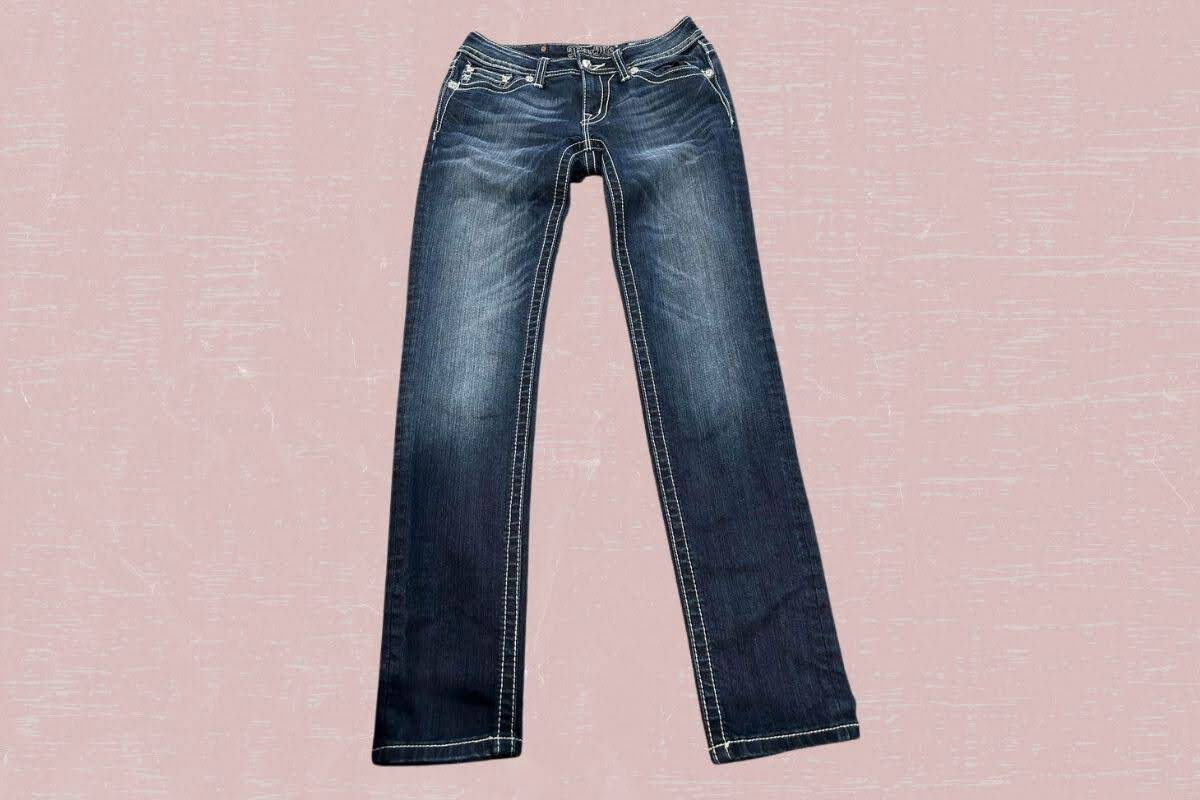 Dark blue faded denim jeans with pockets placed on a pink background