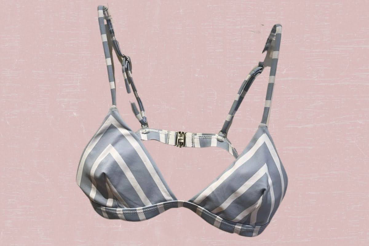 A gray and white soft cup bra with adjustable straps placed on a pink background