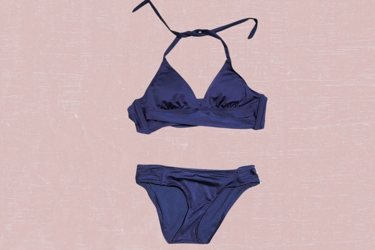 Navy blue two-piece swimsuit placed on a pink background