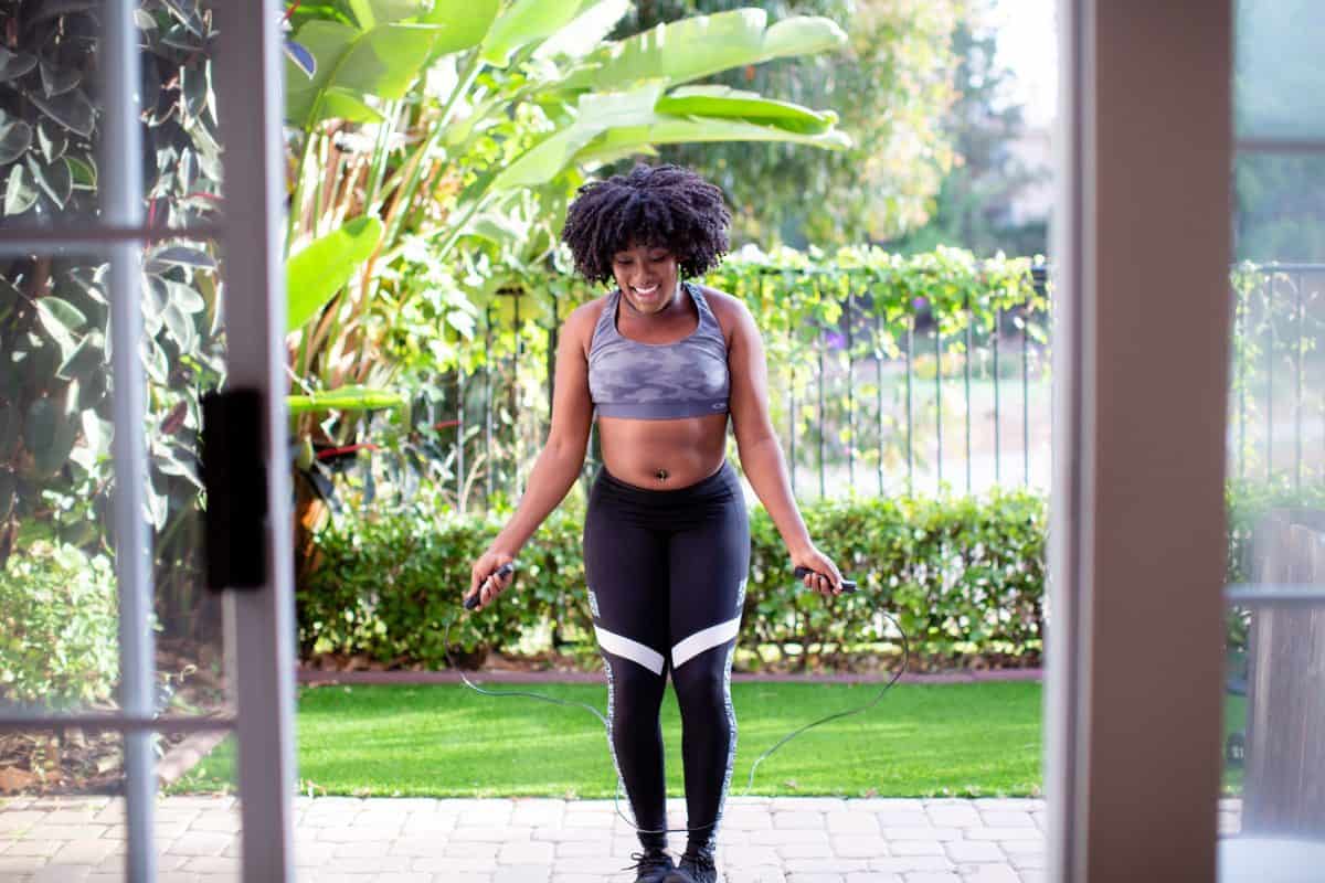 Gray sports bra with a camouflage design and black leggings worn by a woman using a jumping rope