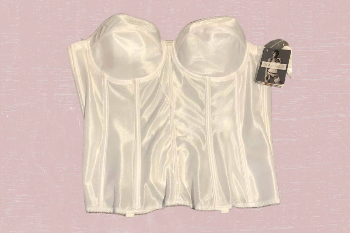 A white torsolette with an underwire and a tag placed on a pink background