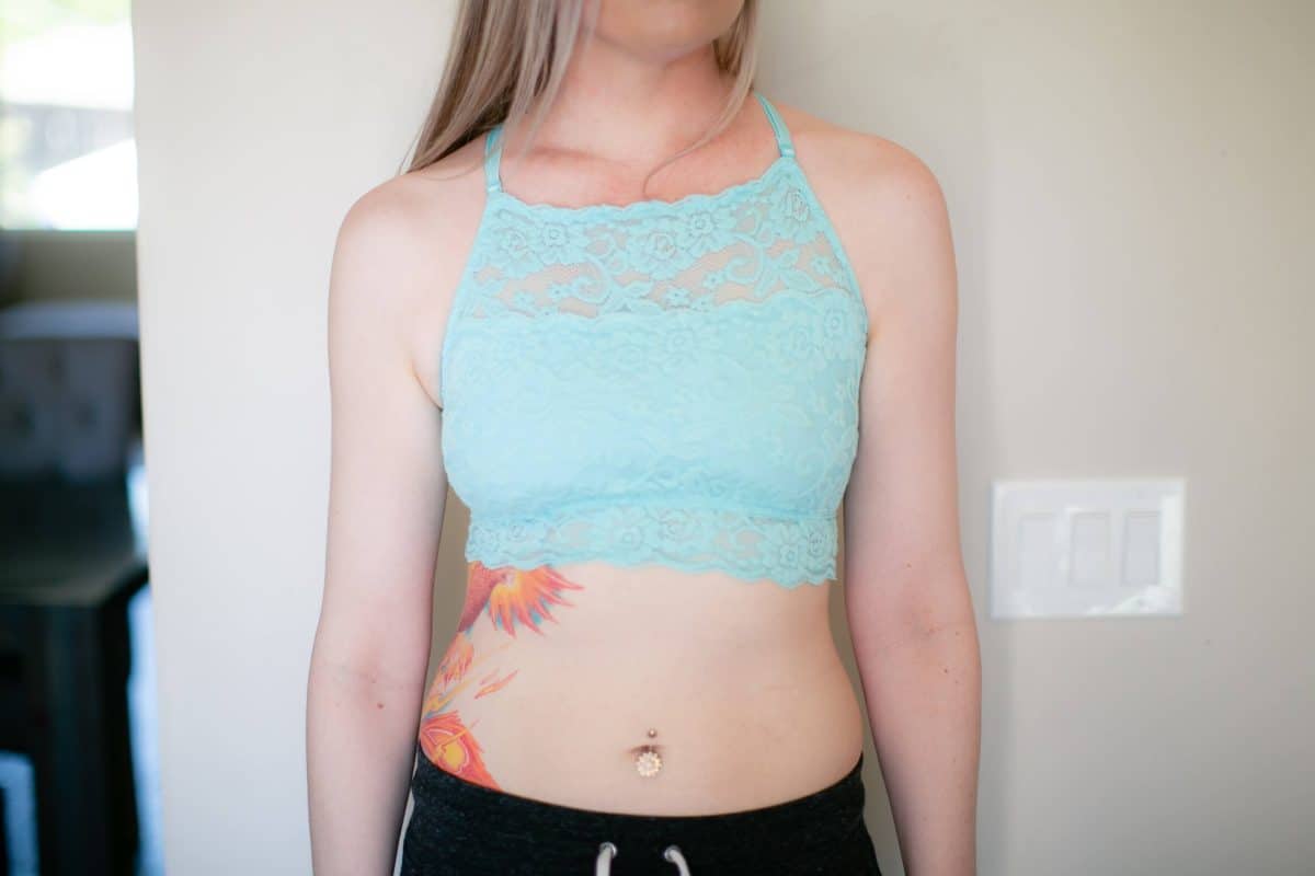 A blue floral lace high-neck bralette and black jogging pants are worn by a woman