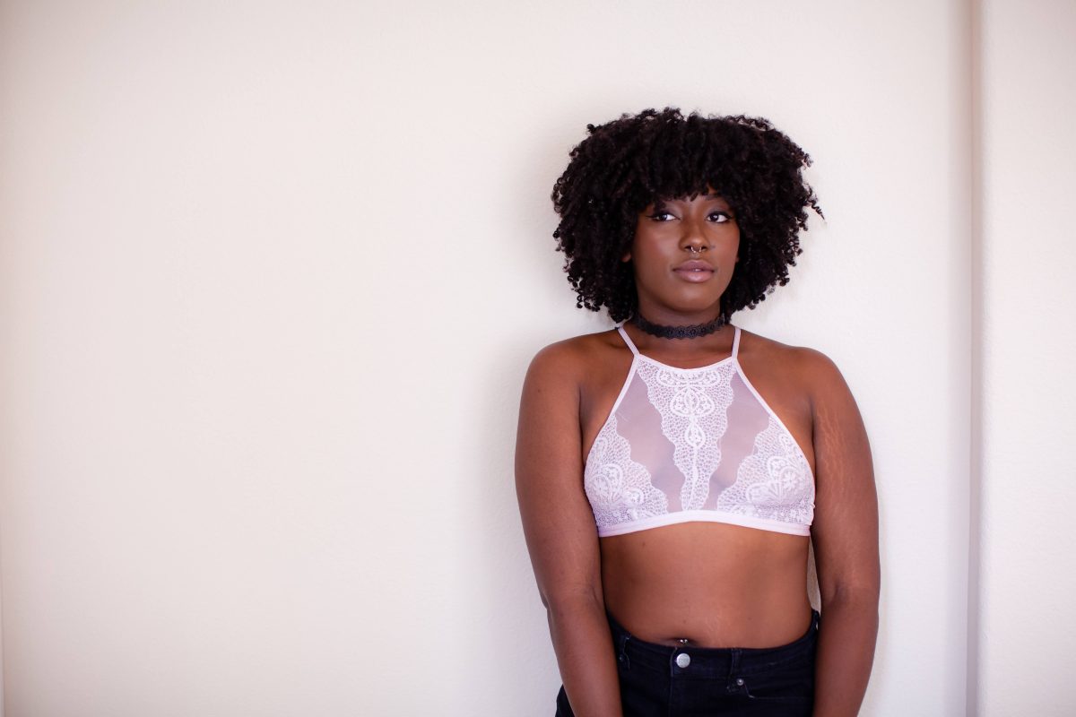 A woman wearing a white high-neck bralette and black denim shorts