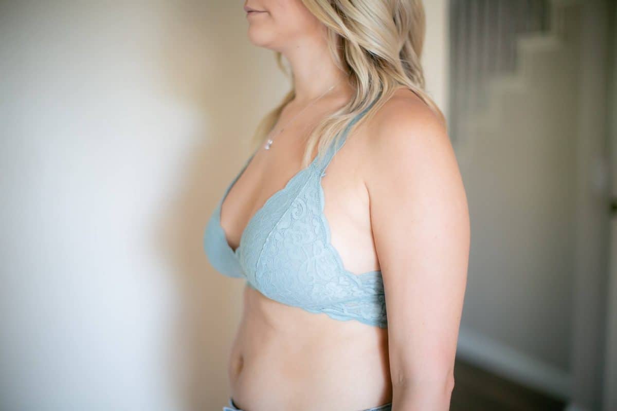 A side view of a woman wearing a blue lace bralette and necklace