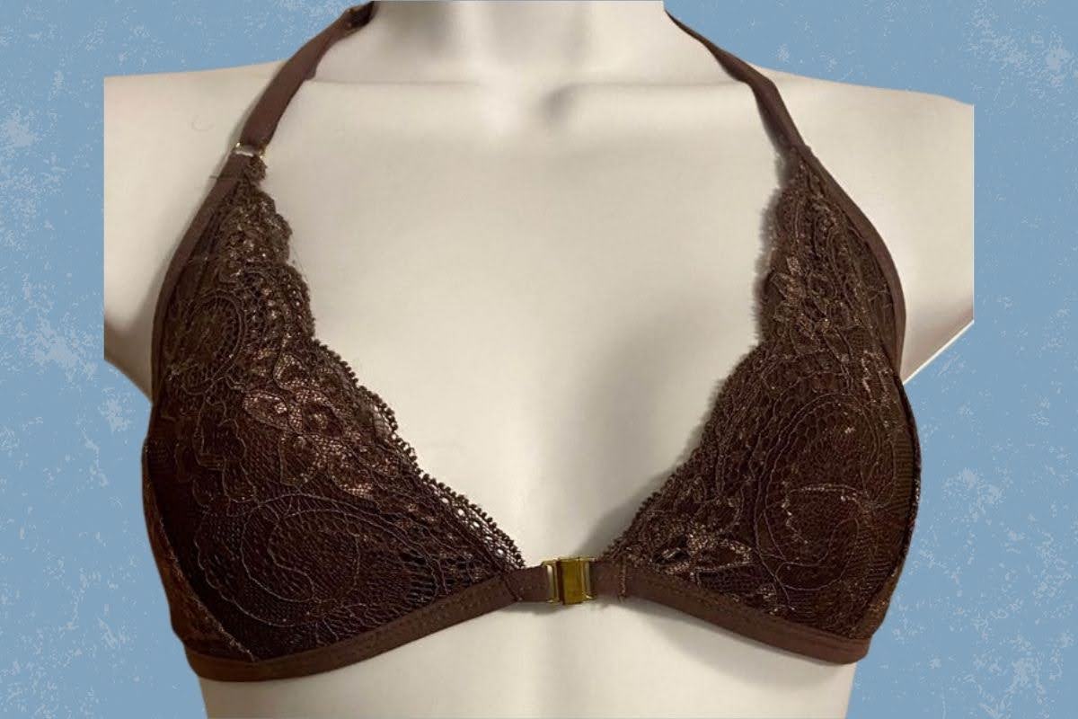 A brown halter bralette with lace design and front clasp placed on a white mannequin