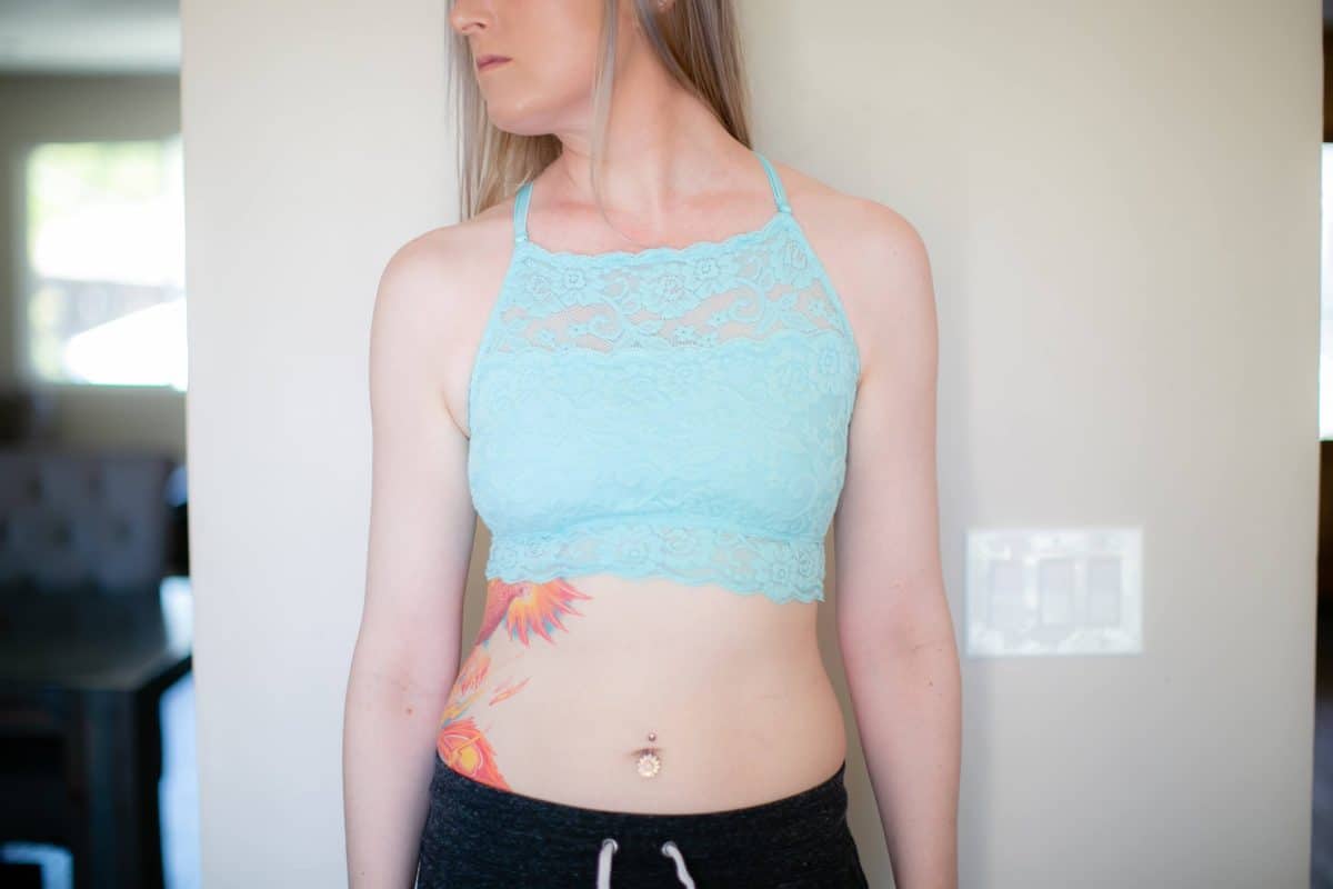 A high-neck longline bralette with a floral lace design and jogging pants worn by a woman