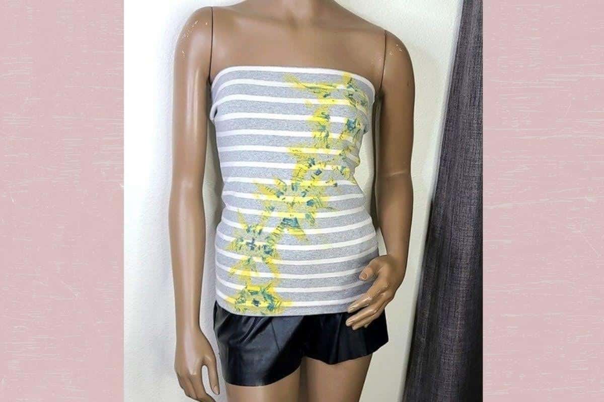 A gray and white tube top and black shorts were placed on a brown mannequin