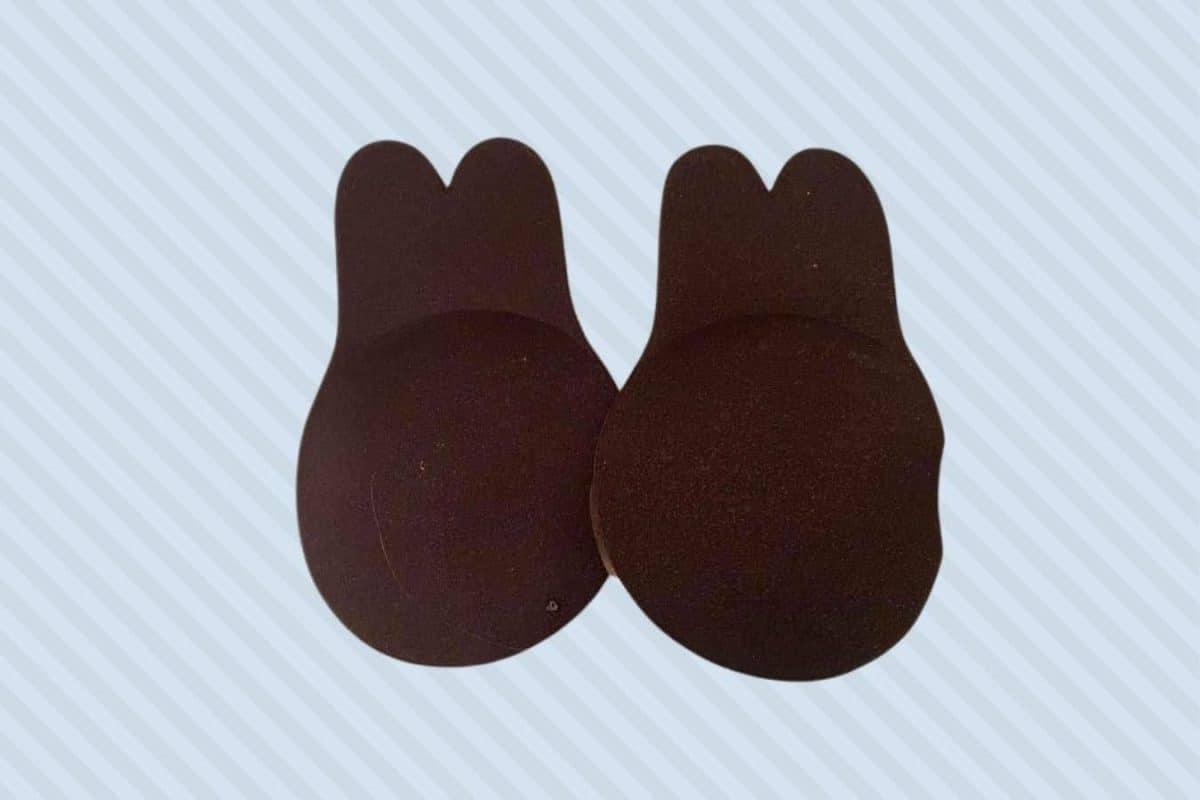 A pair of dark brown adhesive bra tape placed on a blue background