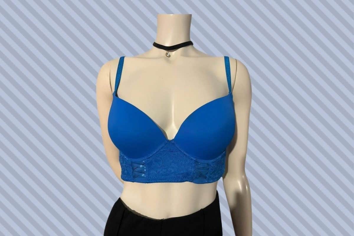 A blue bustier bra with broad bands and black shorts are placed on a white mannequin