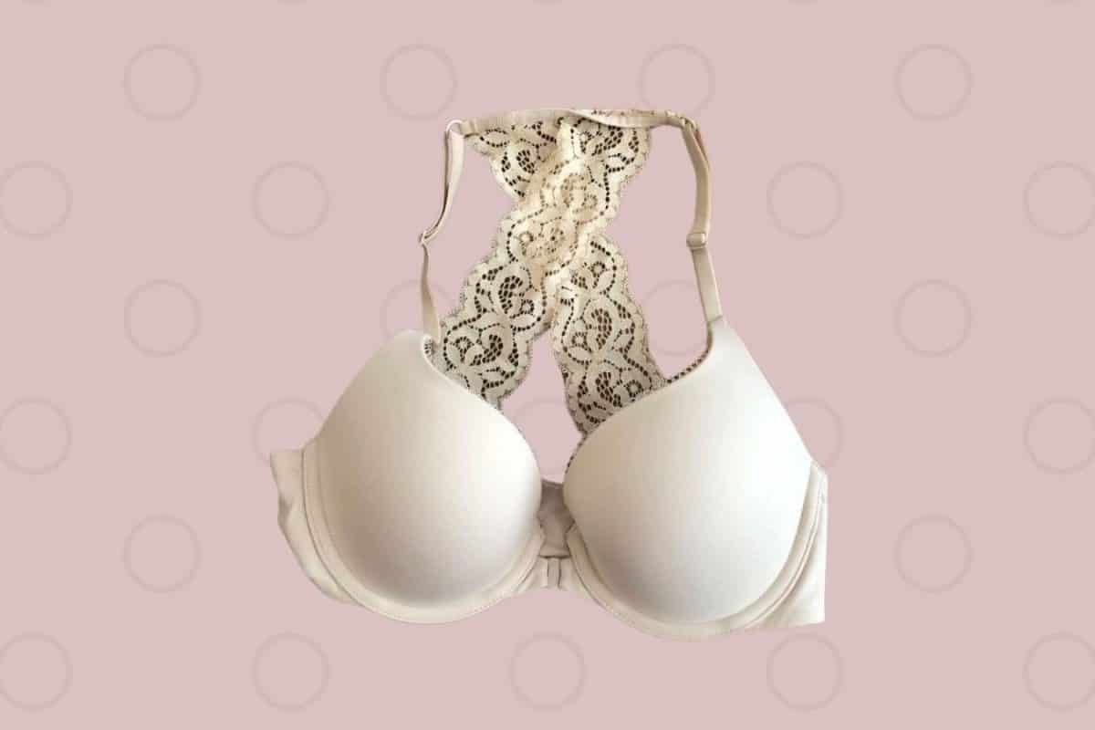 A white underwire racerback bra with a front clasp placed on a pink background