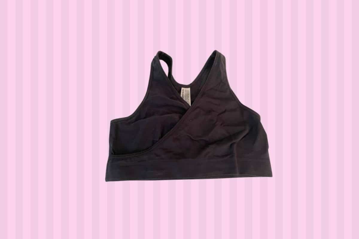 A black sleep bra with a tag placed on a pink background