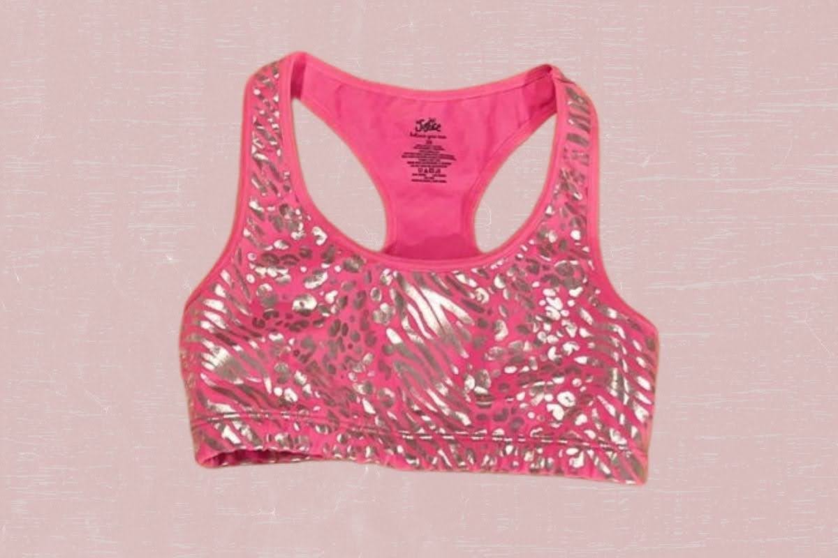 A pink racerback sports bra with a silver design placed on a pink background