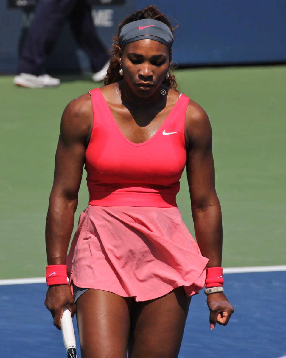Serena Williams wearing a pink tennis outfit while playing on a tennis court