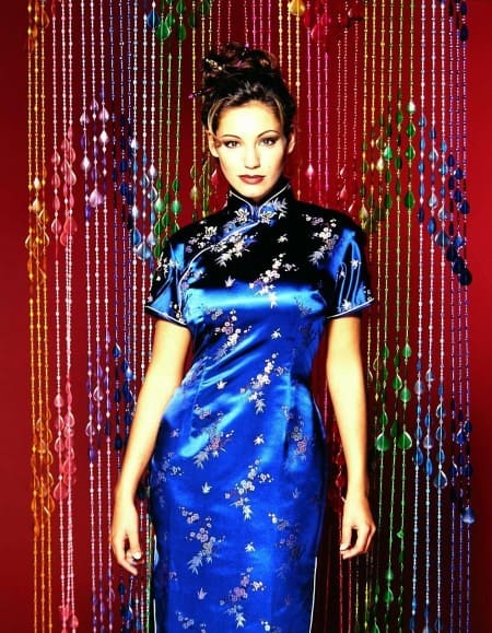 Kelly Brook wearing a blue Cheongsam dress behind a hanging colorful crystal curtain