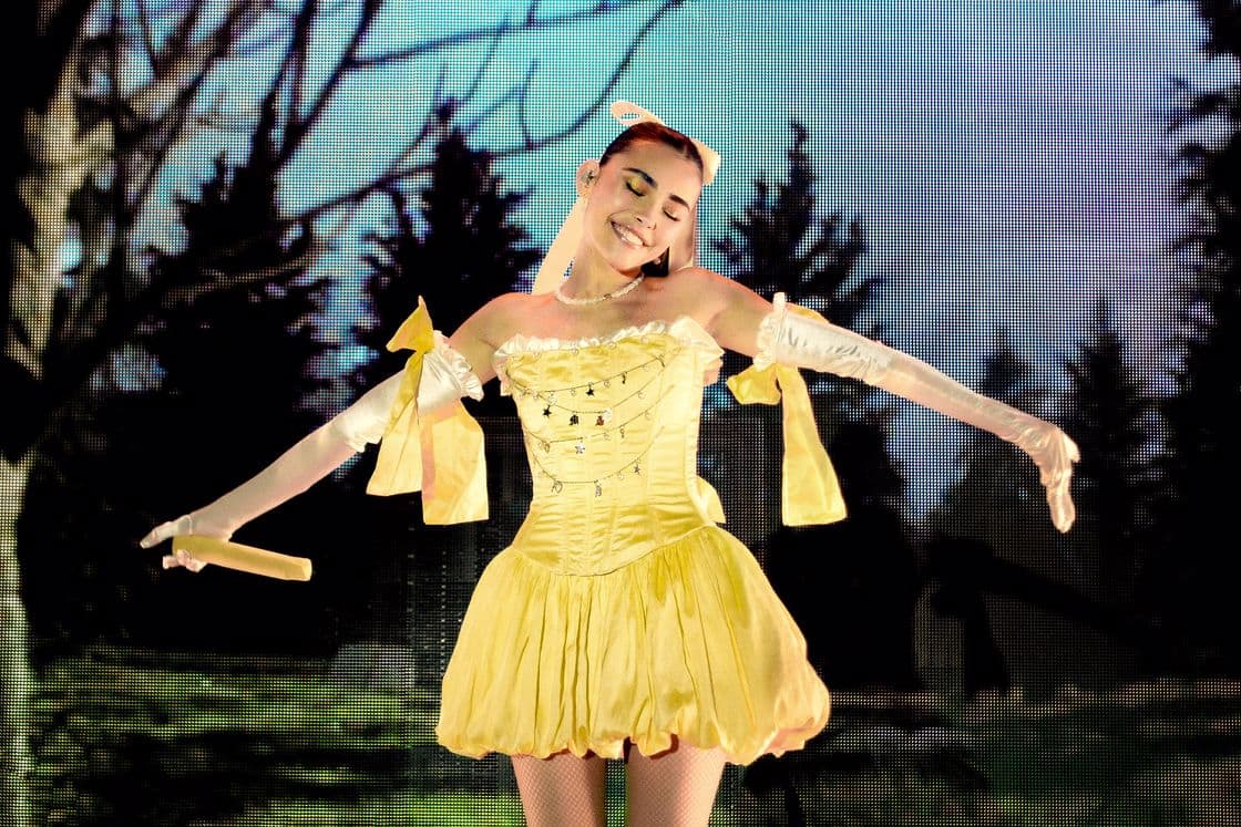 Madison Beer wearing a short yellow dress with big yellow ribbons on her arms