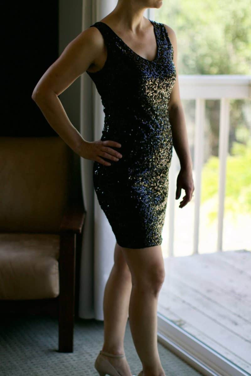 A woman wearing a black bodycon dress with her right hand on her hips