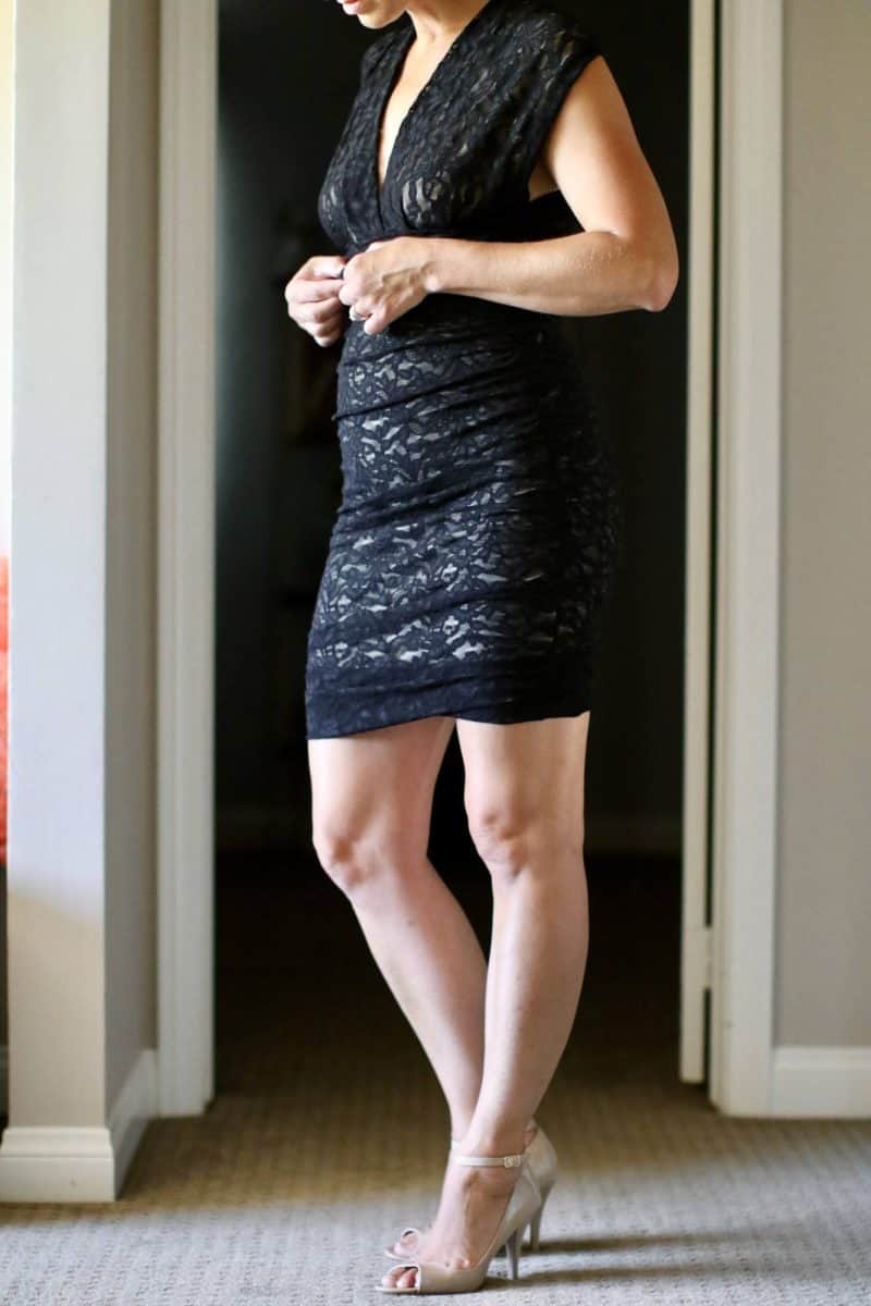 A woman wearing a black bodycon dress fixing the upper part