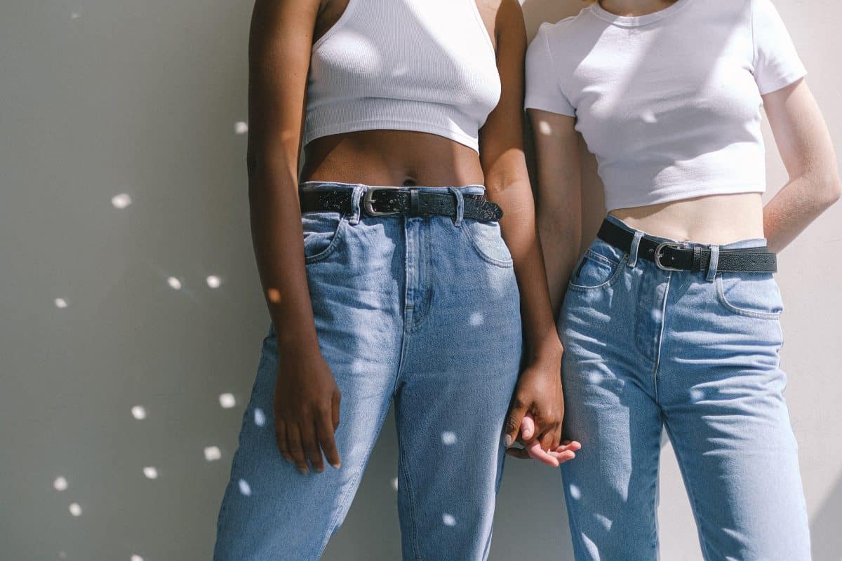A black woman and white woman wearing jeans while holding hands