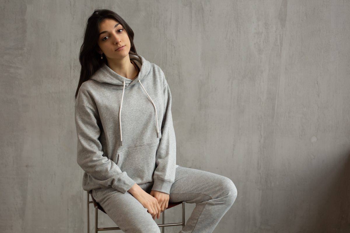 A woman sitting wearing grey sweatpants and jacket