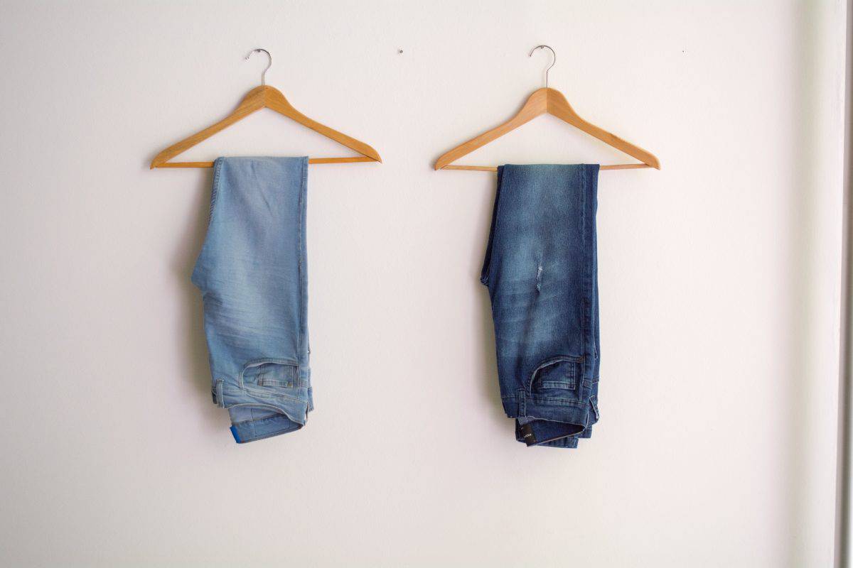 Two folded jeans on separate hangers hanging on the wall