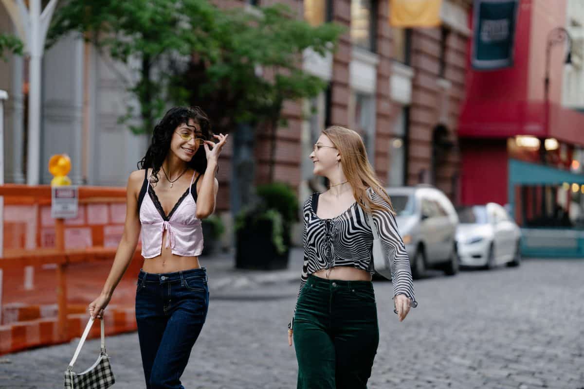 Two ladies walking on a road one wearing low-rise jeans and the other one wearing high-rise jeans