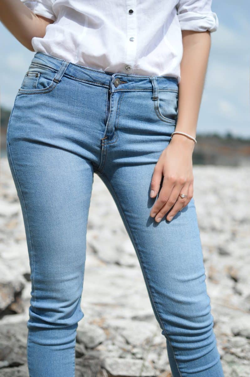 A woman wearing white three fourth sleeve top and a blue slim fit jeans