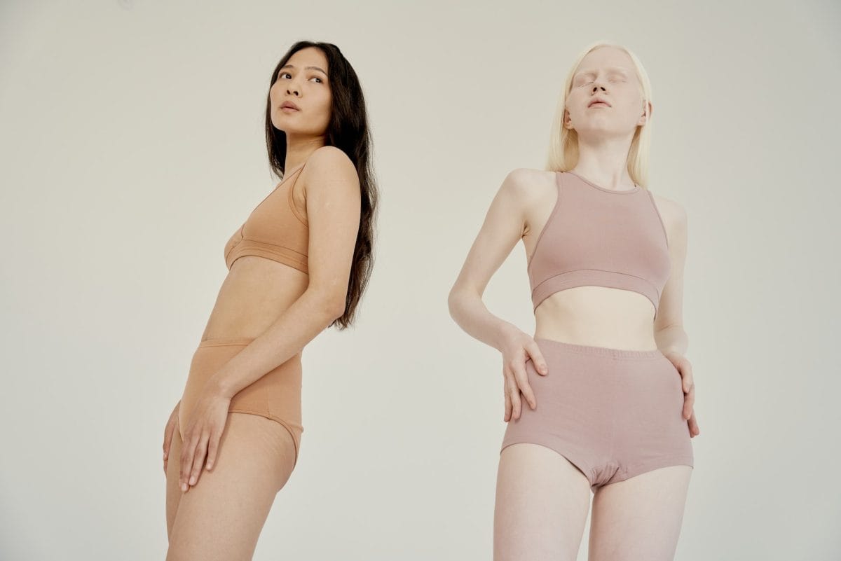 Two women posing an underwear with nude colors such as brown (left) and pink (right)