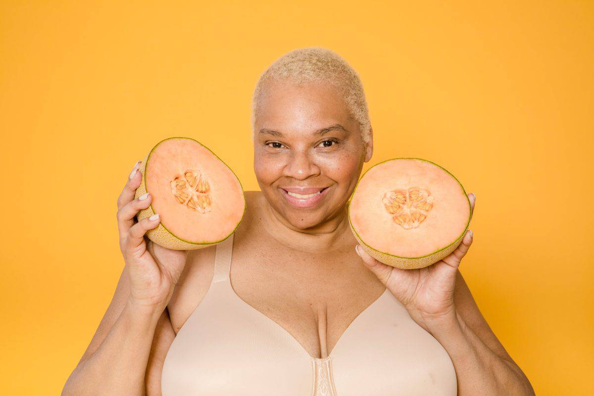 A plus size woman wearing a bra while holding melon fruit