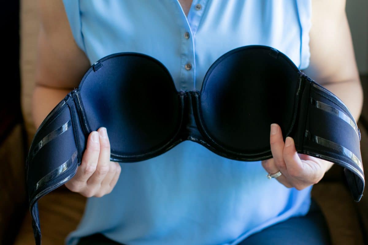 A woman showing the cups of a black push up bra